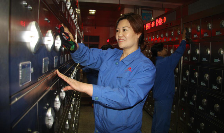 刘秋玲在工作岗位上擦拭现代化全自动矿灯充电架.png