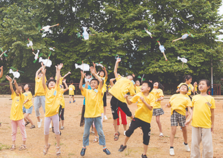 志愿者带孩子们在操场放飞纸飞机。图片来源：株洲新闻网.png