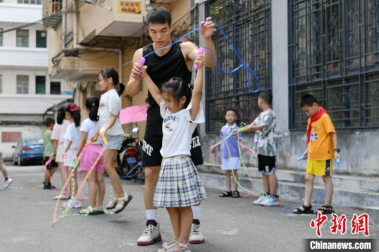 图为大学生志愿者在教孩子们学跳绳。　廖光福 摄